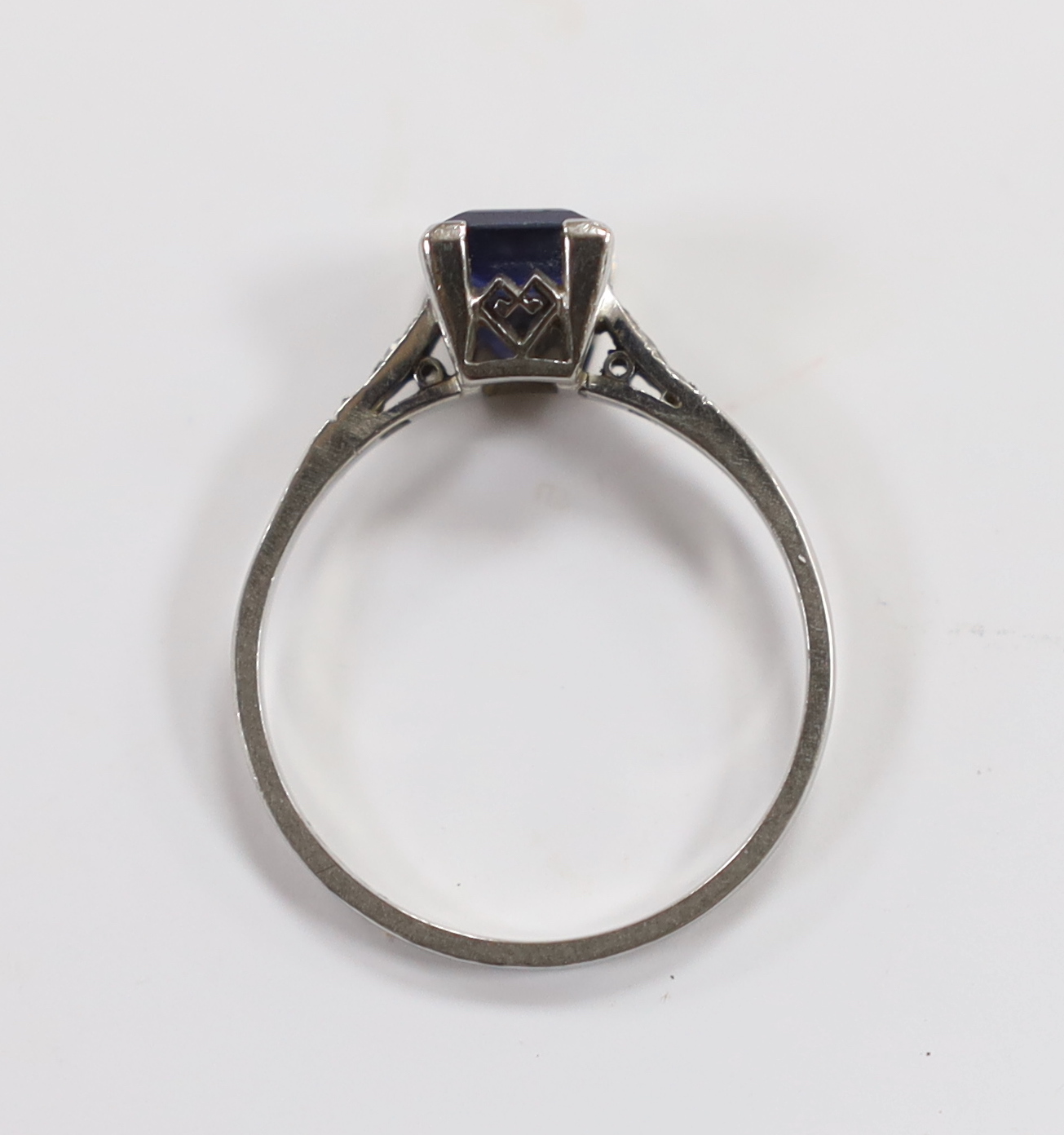 A white metal (stamped plat) and single stone square cut sapphire set ring, with diamond chip set shoulders, size P, gross weight 2.8 gram.